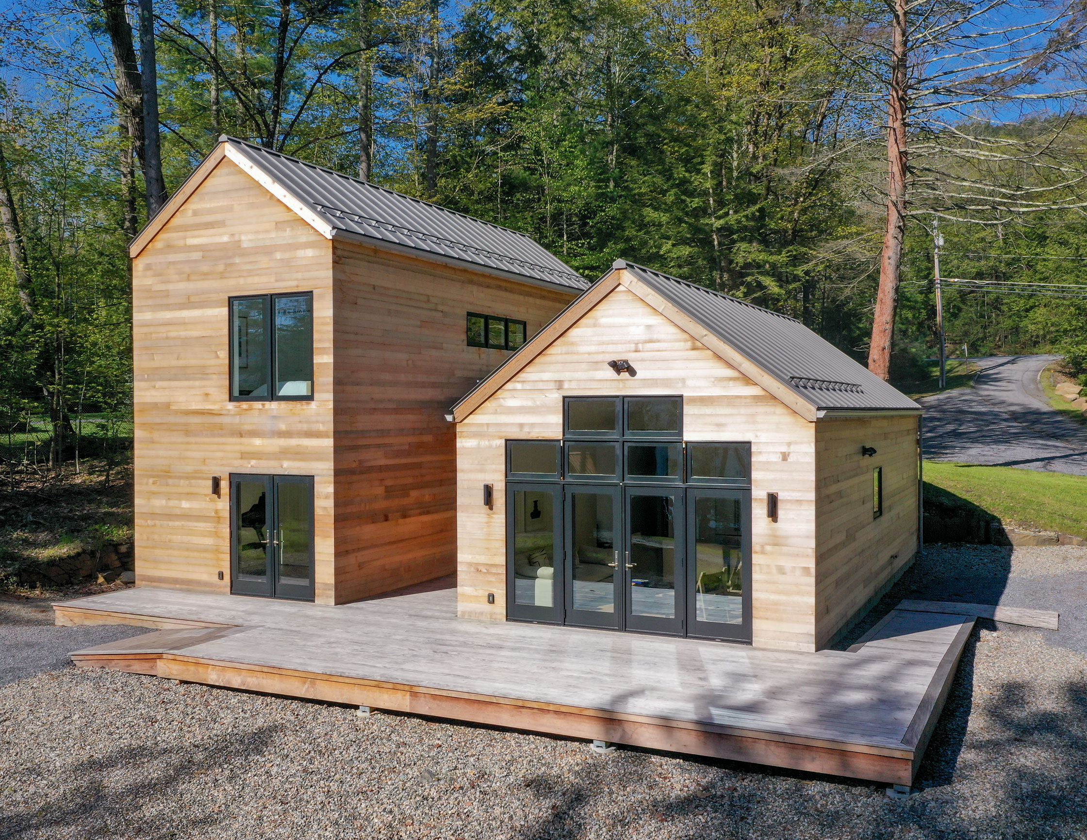 Tucked into the trees behind an overlooking Lake George Summer Home, this modern guest cottage retreat gives peaking Adirondack Views.