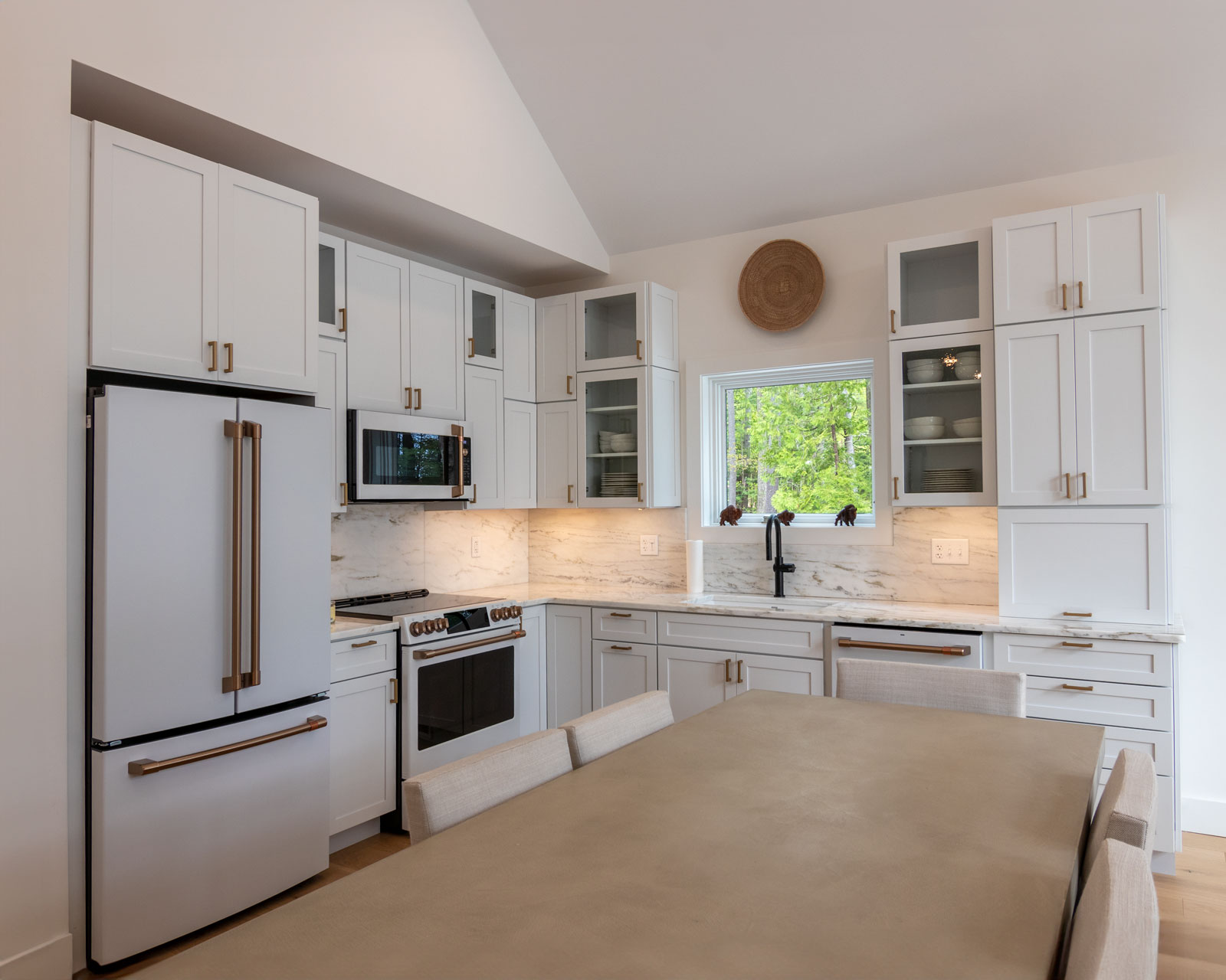 The Rock View Cabin kitchen is adorned with an elegant white interior that was inspired by historic lakeside camps. The white with bronze hardware Cafe Appliances gives a classy and refined look.