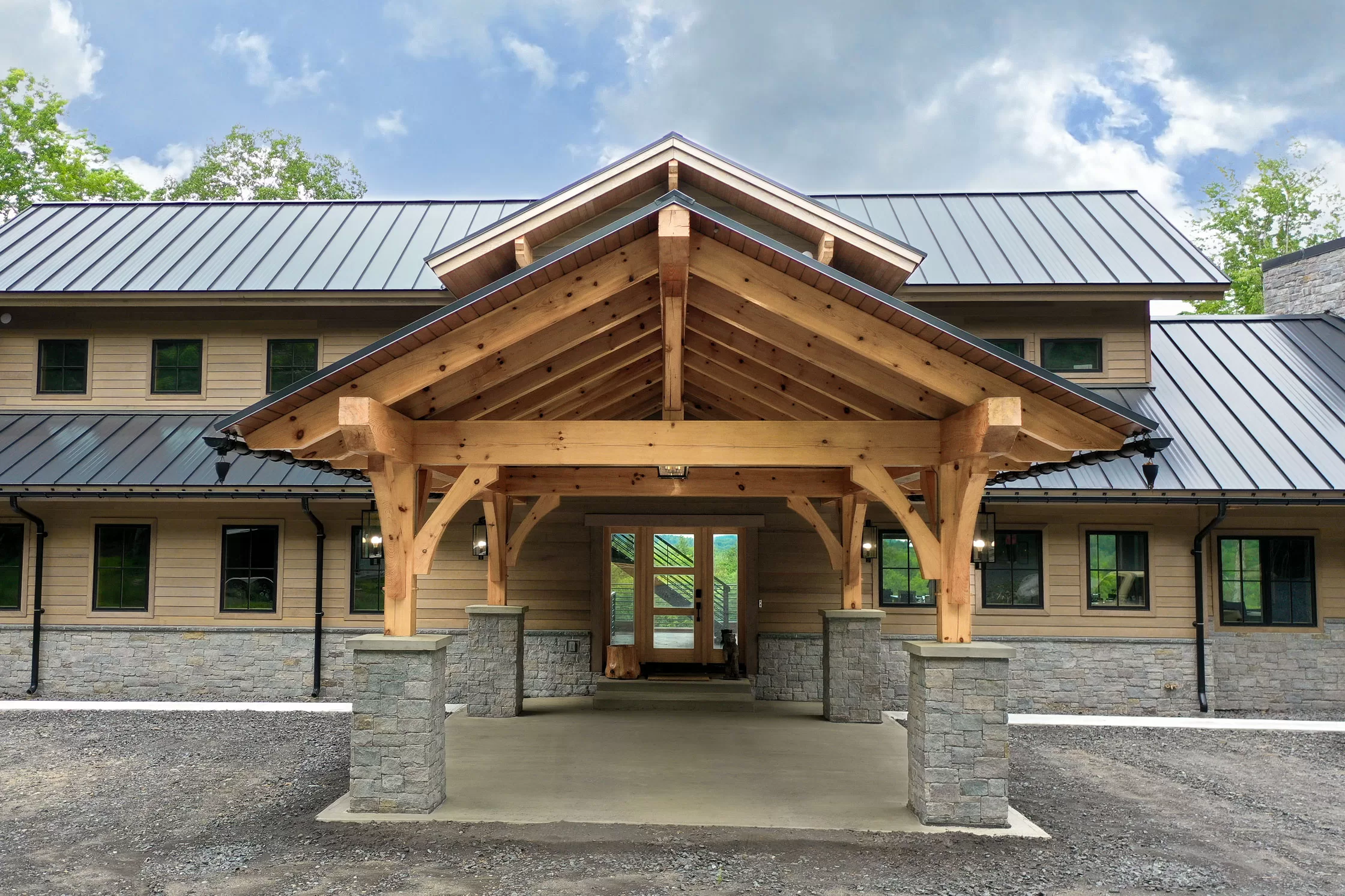 The long, tree-lined driveway keeps the world at bay, and as you approach the house, a porte-cochère welcomes you in true mountain-lodge style. This covered entrance not only adds grandeur but also offers a sheltered drop-off area for guests, making arrivals and departures seamless even in winter weather.